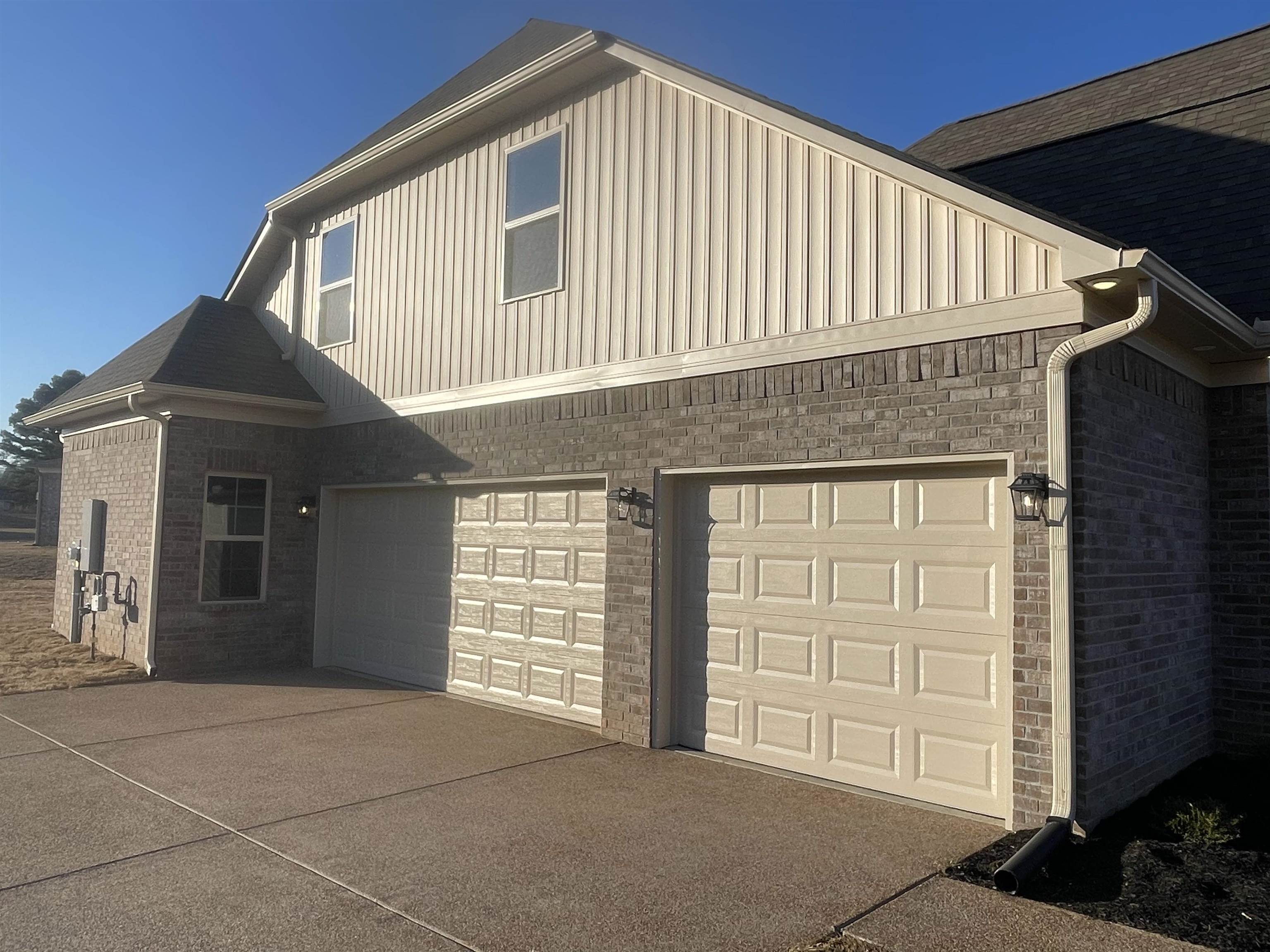 19 Columbia Way Atoka, TN 38004 - Photo 8 of 28 View of side of home featuring concrete driveway, board and batten siding, brick siding, and an attached garage