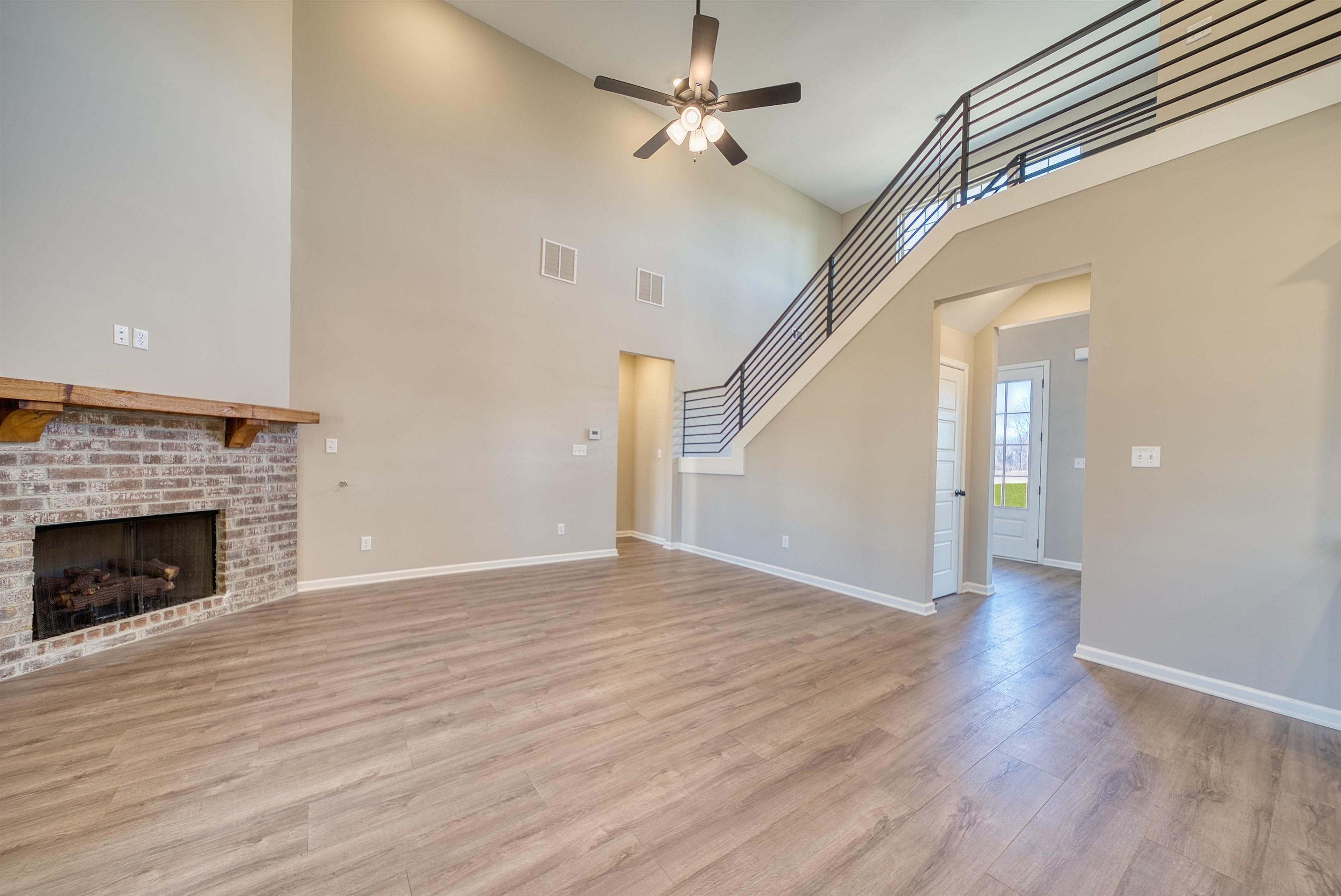 19 Columbia Way Atoka, TN 38004 - Photo 10 of 40 Unfurnished living room with ceiling fan, light wood finished floors, a fireplace, and a high ceiling
