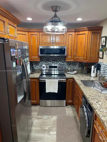 a kitchen with stainless steel appliances granite countertop a stove a sink dishwasher and a refrigerator