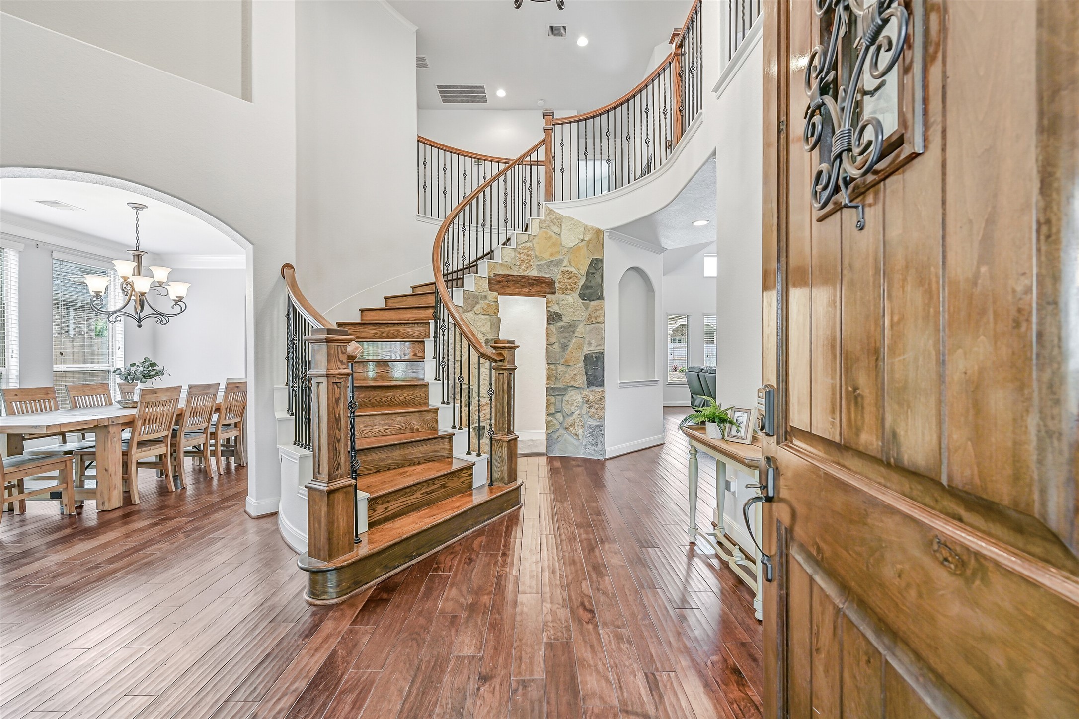 1008 Point Isabel Lane Friendswood, TX 77546 - Photo 5 of 50 Enter into a grand foyer with soaring ceilings, rich engineered wood floors, and a sweeping staircase with iron balusters, creating an impressive first impression with views that extend into the heart of the home.