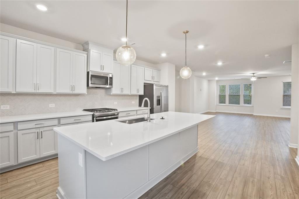 26 Peeples Drive Lawrenceville, GA 30046 - Photo 3 of 24 a large kitchen with kitchen island a stove a sink a center island and wooden floor
