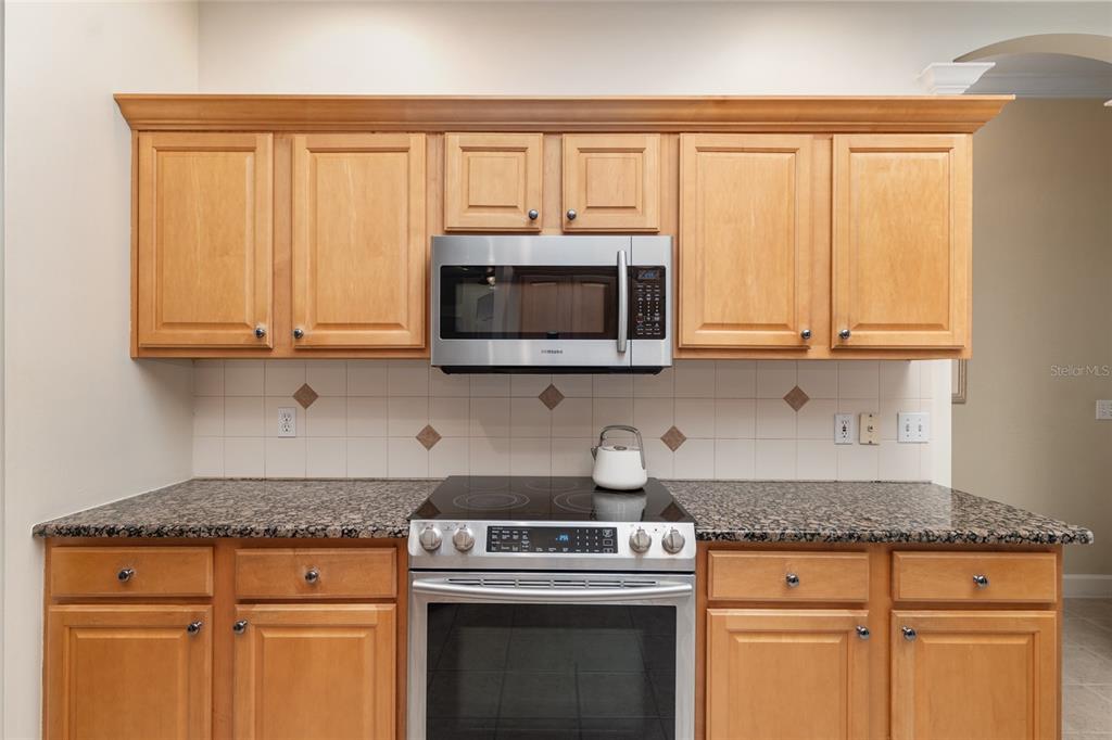 9513 Southwest 33 Lane Gainesville, FL 32608 - Photo 27 of 68 a kitchen with granite countertop white cabinets and stainless steel appliances