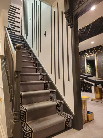 a view of staircase with lots of frames on wall and a dining table