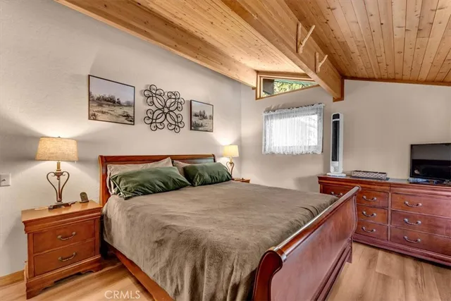 a bedroom with a bed and a flat tv screen on dresser