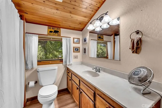 a bathroom with a sink a mirror a toilet and a window