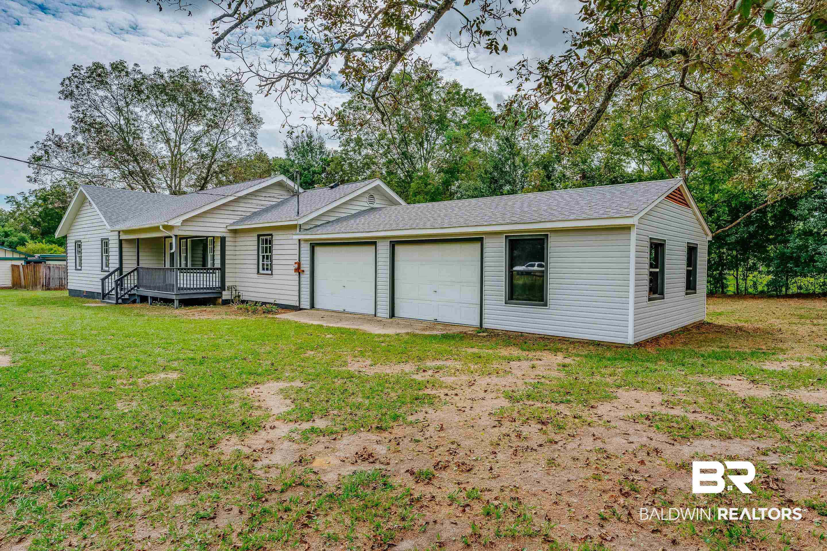 8001 16th Street Irvington, AL 36544 - Photo 2 of 35 Single story home with roof with shingles, a front lawn, an attached garage, and view of wooded area