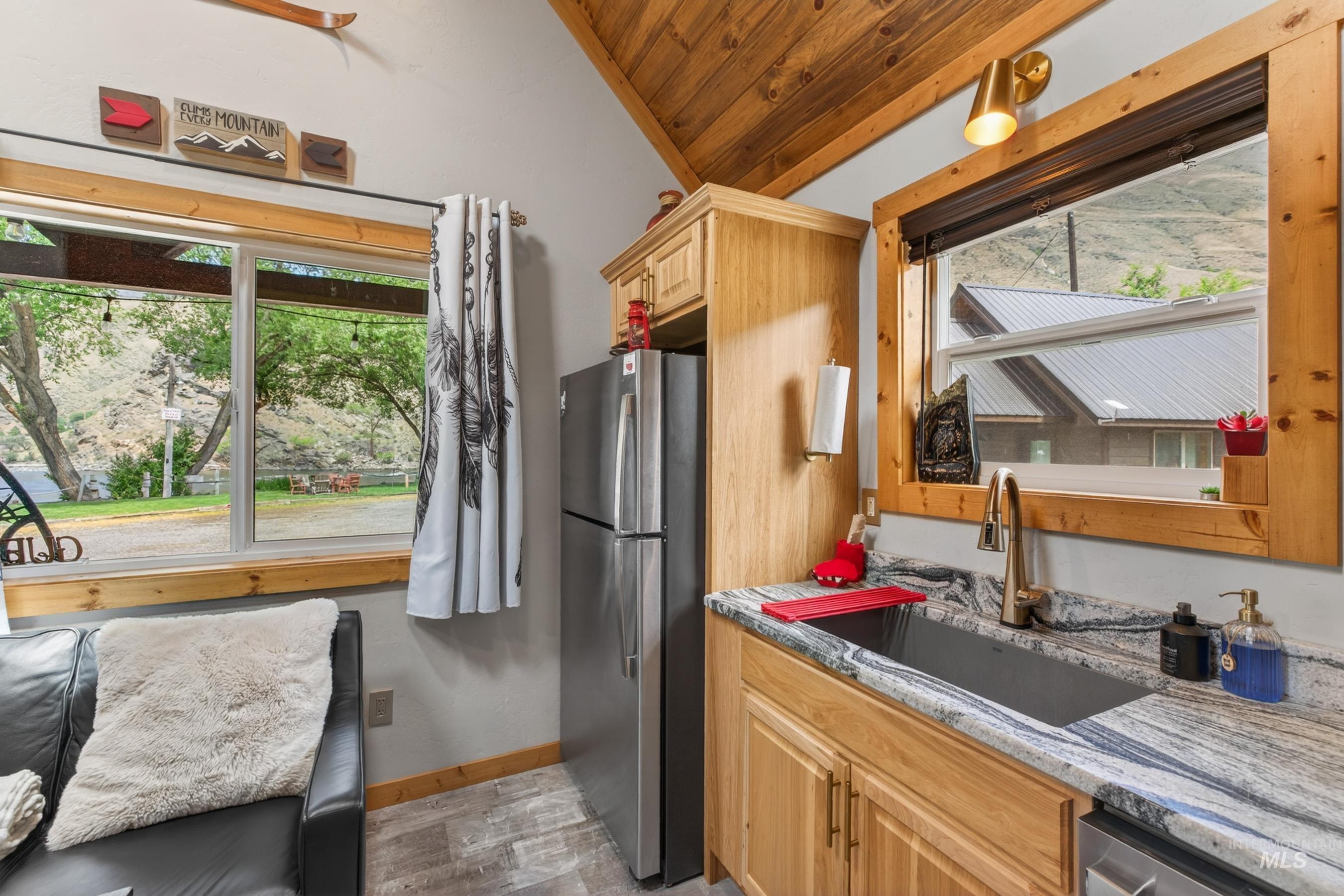 1432 Salmon Drive Riggins, ID 83549 - Photo 12 of 39 Kitchenette featuring light wood-finish cabinetry, a single basin sink with a gold-tone faucet, and a stone-finish countertop
