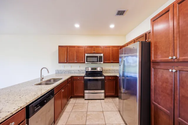 a kitchen with stainless steel appliances granite countertop a refrigerator and a sink