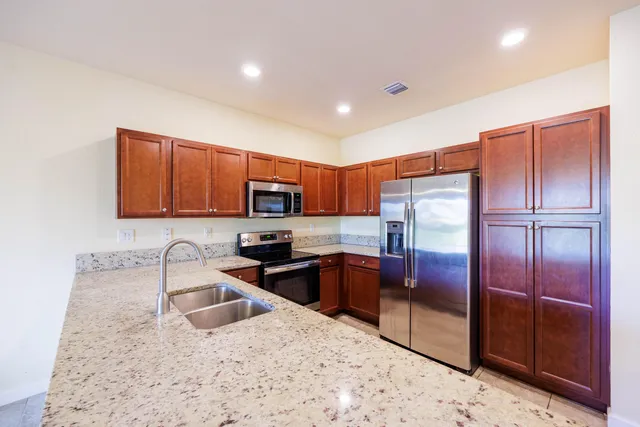 a kitchen with stainless steel appliances granite countertop a refrigerator a sink a stove a microwave and island