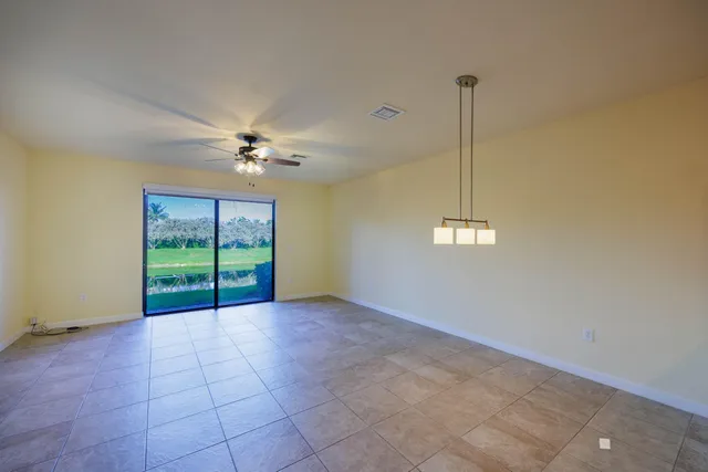 a view of an empty room with window and chandelier fan