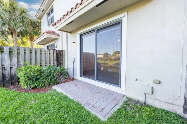 a view of yellow house with a yard and potted plants