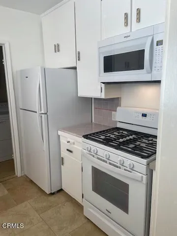 a kitchen with stainless steel appliances white cabinets and a stove a refrigerator with white countertops