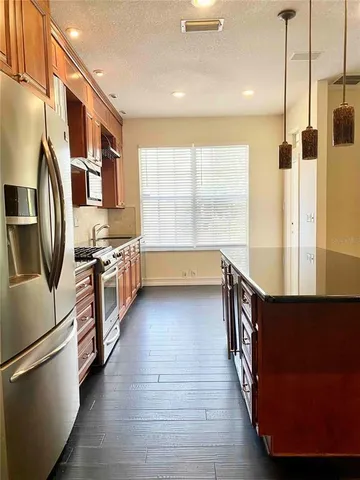 a kitchen with stainless steel appliances a refrigerator a stove a sink and white cabinets with wooden floor