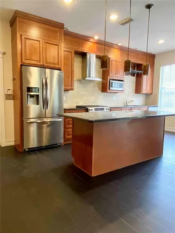 a kitchen with stainless steel appliances granite countertop a refrigerator a oven and a sink