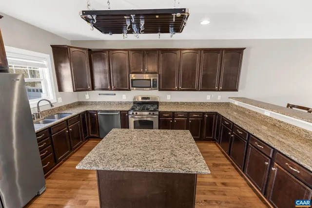 a kitchen with stainless steel appliances granite countertop wooden cabinets sink and stove