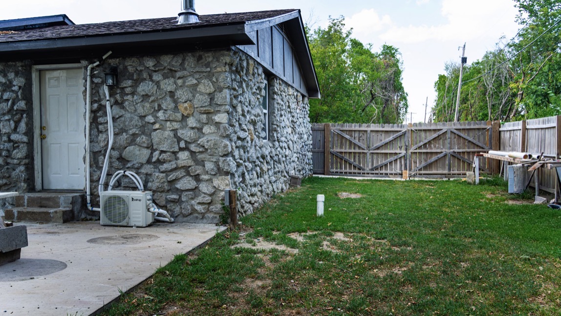 415 Martin Street Muskogee, OK 74401 - Photo 5 of 6 Stone veneer exterior, concrete patio, grass lawn, wood plank fencing, privacy gate
