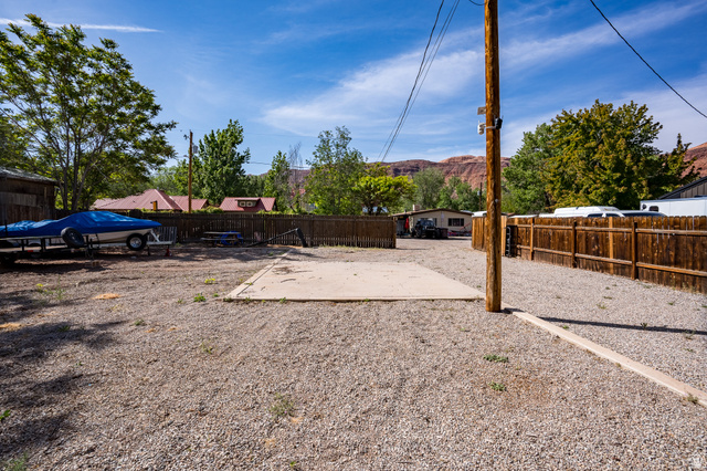 186 West Center Street Moab, UT 84532 - Photo 11 of 15 Expansive gravel yard featuring a concrete pad, mature trees, and wood fencing