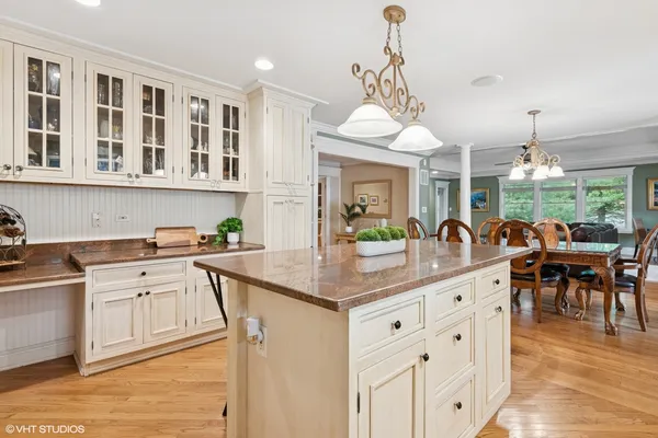 a kitchen with stainless steel appliances granite countertop a stove a sink a dining table and chairs with wooden floor