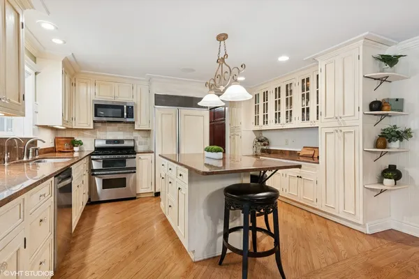 a kitchen with granite countertop a stove a sink dishwasher a refrigerator and a dining table with wooden floor