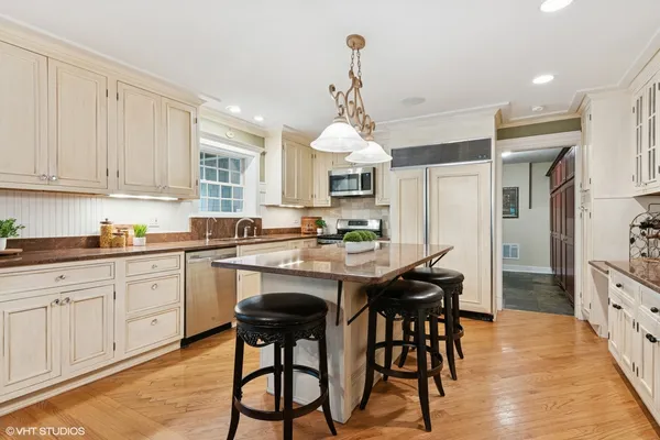 a kitchen with stainless steel appliances kitchen island granite countertop a table chairs sink and cabinets
