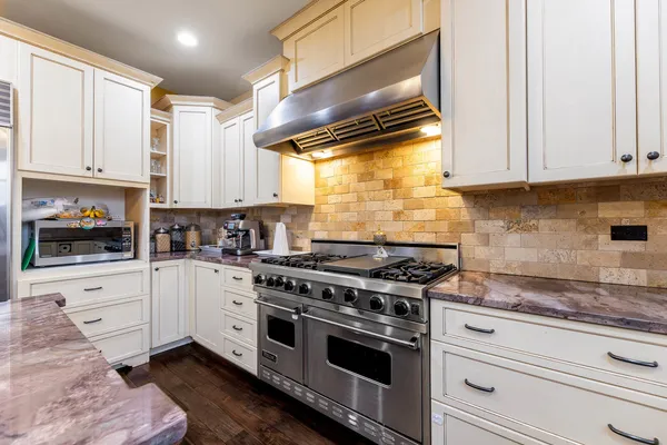 a kitchen with stainless steel appliances white cabinets and a stove top oven