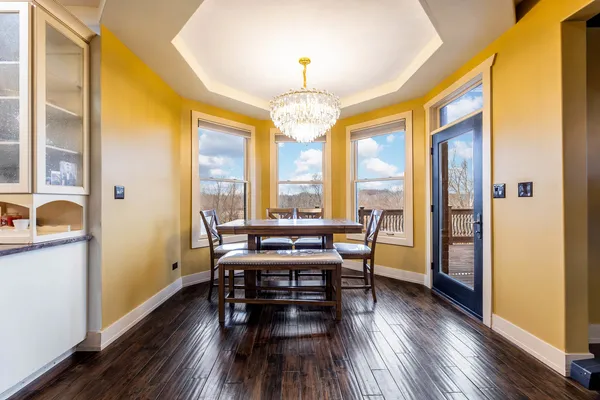 a dining room with wooden floor a chandelier a wooden table and chairs