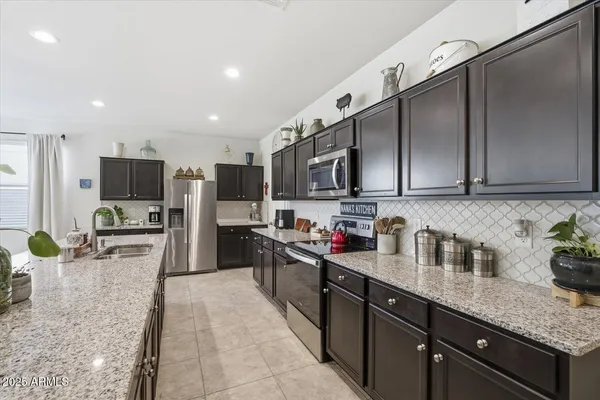 a kitchen with stainless steel appliances granite countertop a sink dishwasher stove top oven and refrigerator