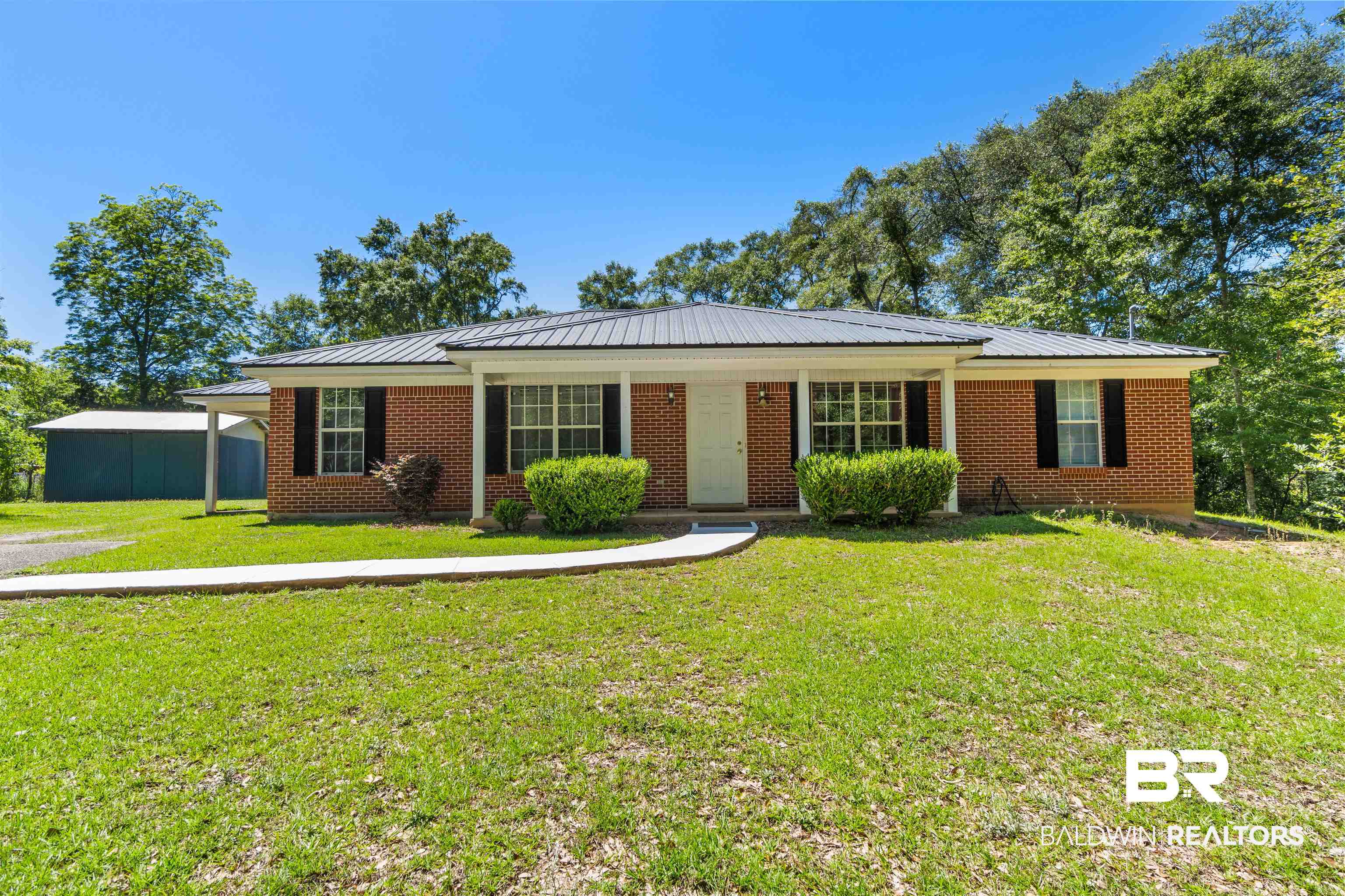 35893 Pine Road South Stapleton, AL 36578 - Photo 2 of 31 Brick exterior featuring a covered front porch with white columns, a dark metal roof, and black louvered shutters