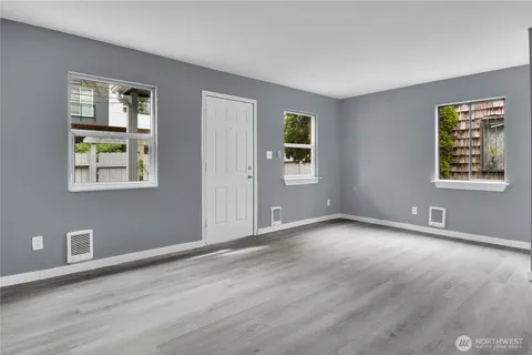 a view of an empty room with window and wooden floor