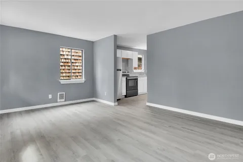 a view of an empty room with a window and wooden floor