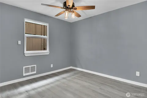 a view of an empty room with window and wooden floor