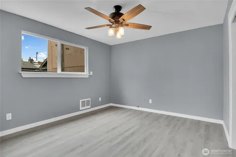 a view of an empty room with window and wooden floor