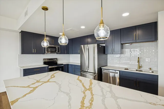 a kitchen with stainless steel appliances a stove a refrigerator a sink and a wooden floor