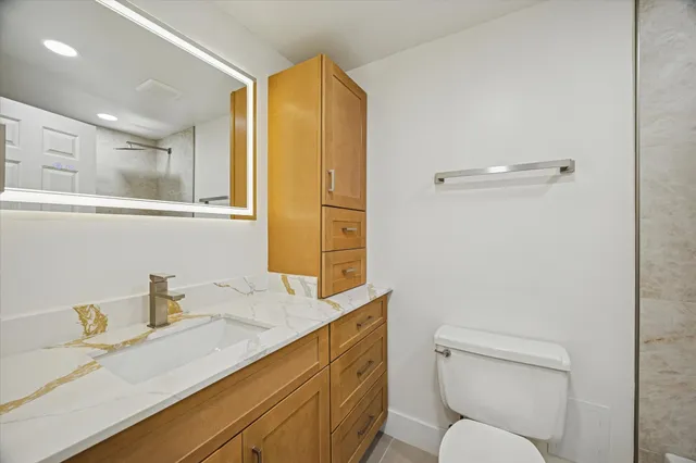 a bathroom with a granite countertop sink mirror vanity and toilet