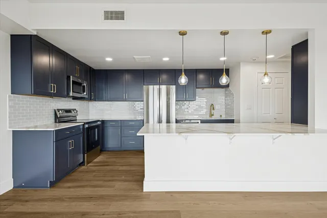 a large kitchen with stainless steel appliances kitchen island granite countertop a stove a sink and a refrigerator