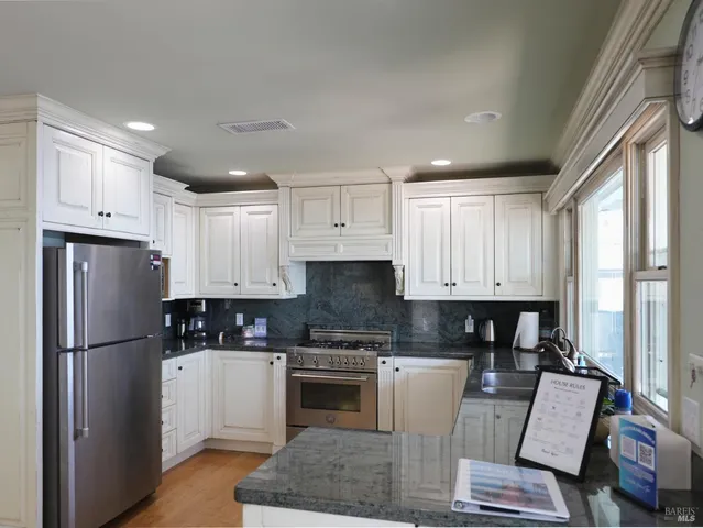 a kitchen with granite countertop a refrigerator stove top oven and sink