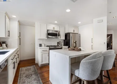 a kitchen with kitchen island granite countertop a sink a stove a refrigerator cabinets and a dining table