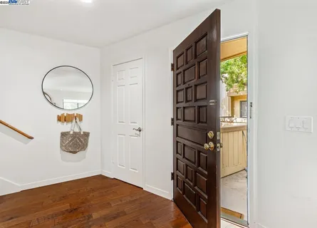 a view of an empty room with wooden floor and windows
