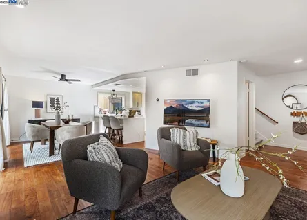 a living room with furniture a flat screen tv and kitchen view