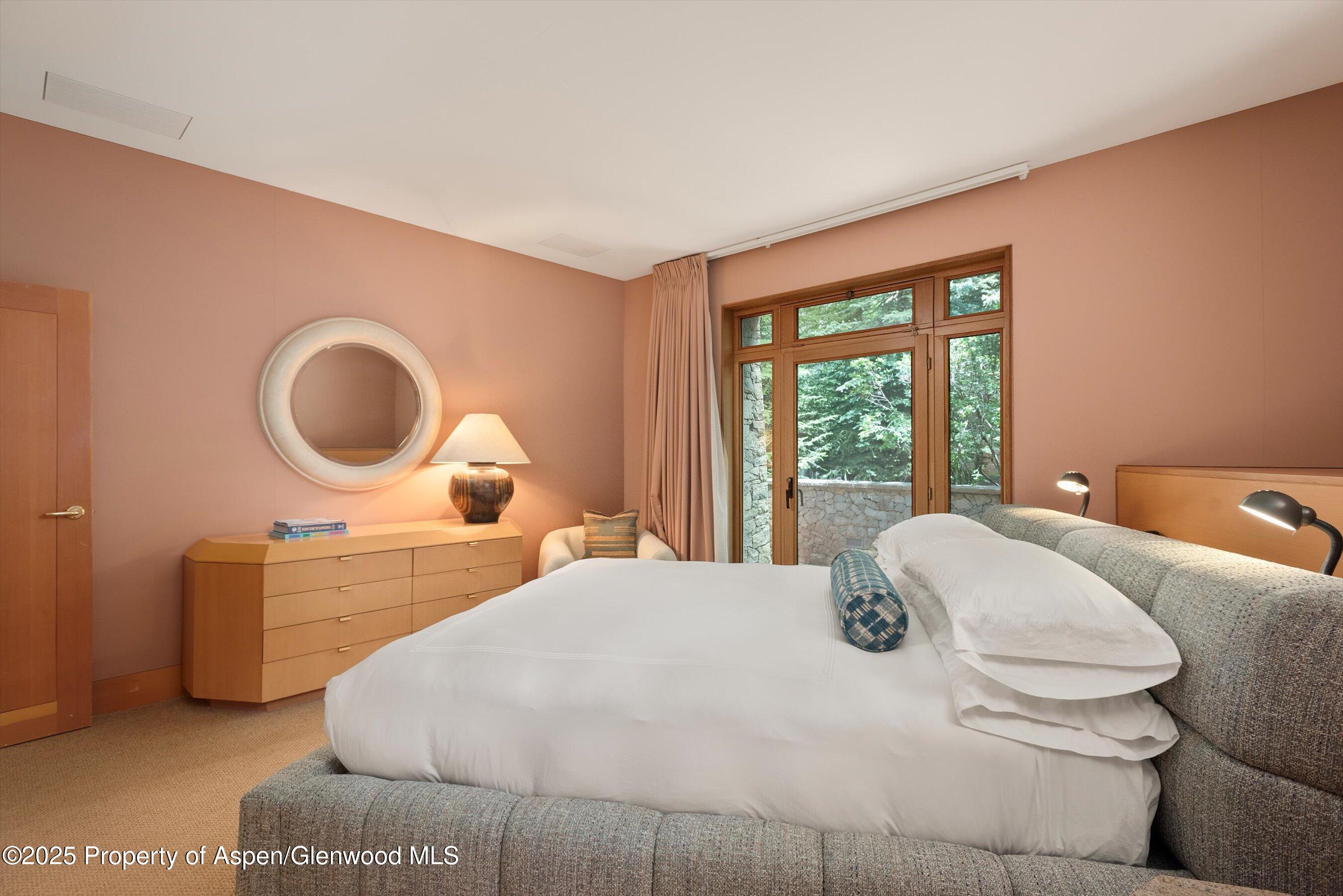 800 Roaring Fork Road Aspen, CO 81611 - Photo 29 of 37 a bedroom with a bed a mirror and a large window