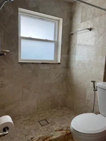 a white toilet sitting next to a shower