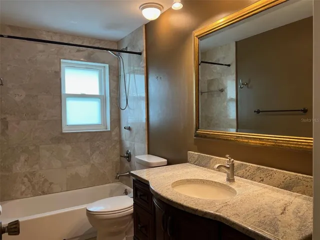 a bathroom with a granite countertop sink toilet and shower
