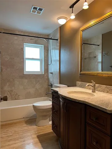 a bathroom with a granite countertop sink toilet mirror and bathtub