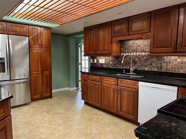 a kitchen with stainless steel appliances granite countertop a refrigerator a sink and wooden cabinets