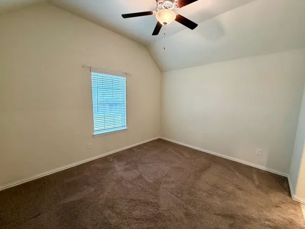 an empty room with a chandelier fan and windows