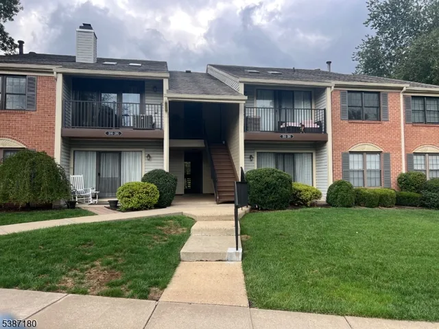 a view of a brick house with a yard and plants