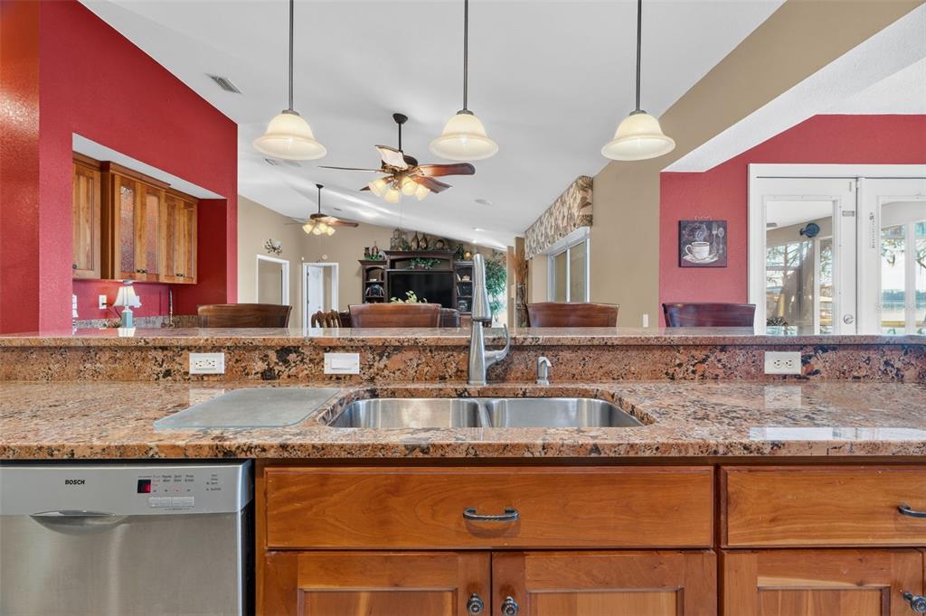 115 Hunting Lodge Drive Inverness, FL 34453 - Photo 19 of 59 a kitchen with granite countertop a sink a stove and a wooden cabinets