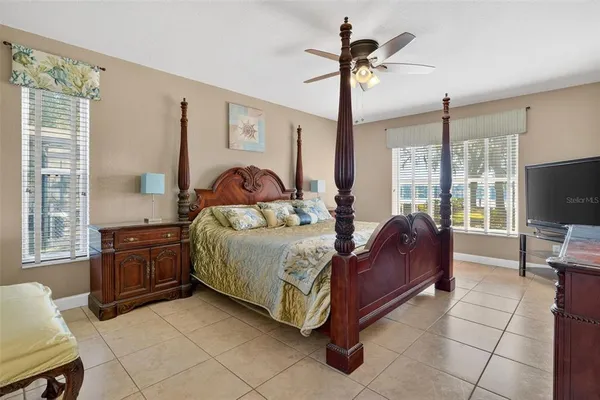 a spacious bedroom with a bed a dresser and potted plants