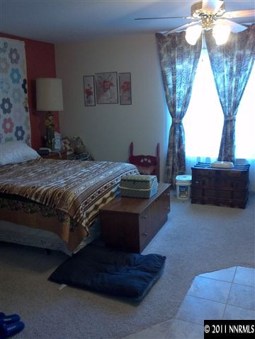 60 Ghost Rider Drive Reno, NV 89511 - Photo 7 of 13 a bed sitting in a bedroom next to a chandelier and a larger window