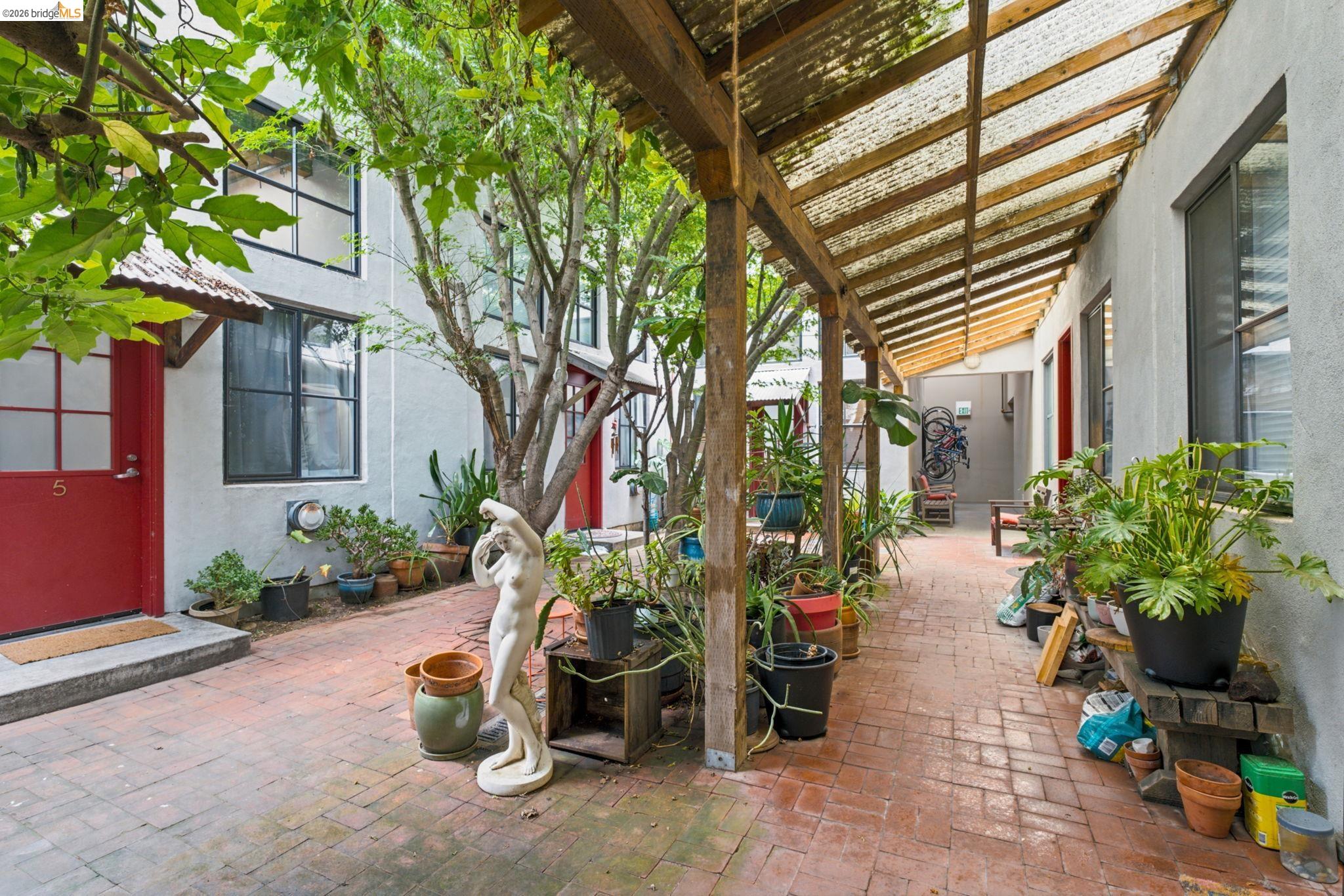 1920 Union Street, Unit 9 Oakland, CA 94607 - Photo 34 of 35 Brick paver courtyard featuring an open-air wood beam pergola with a translucent roof